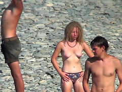 Chicas nudistas exponen cuerpos en la playa.